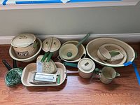 Wide view of all 23 pieces including flour container, colanders, graters, basin, and assorted kitchen tools with green handles.