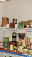Full view of two shelves holding assorted vintage tins.