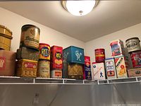 Overview of vintage advertising tins on a shelf including Bachman, Ritz, and others showing colorful branding and labels.
