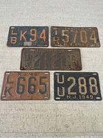 Five vintage New Jersey license plates laid out showing rust and wear