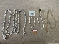 Full lot with all 10 pieces including necklaces, earrings, rings, bracelets and pin laid out on table