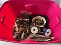 Red plastic storage tote filled with assorted lamp repair parts, mini lamps, lamp sockets, wiring, and brass fittings.
