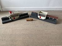 Pair of two Lionel 464 saw mill models placed on floor with small wooden log bundles in center