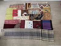 Top-down photo of an assortment of placemats, mini rugs, and a table runner laid out flat on the floor showing varying shapes and patterns.