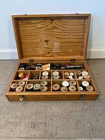 Open wooden sewing box showing all compartments and contents including wooden spools and accessories