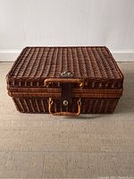 Front view of the rectangular wicker basket showing woven texture, hinged lid, and locking latch.