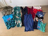 Various women's clothing items laid out on floor, displaying different dresses, tops, and a sweater