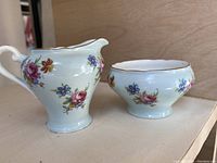 Photo showing the light blue creamer and sugar bowl with floral patterns and gold rims.