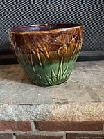 Front and side view of the vintage green and brown glazed ceramic pot showing embossed floral motifs and color gradient.