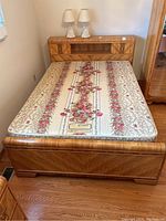 Full view of bed frame with retro wood-style headboard, footboard, and floral mattress on wooden floor.