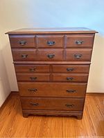 Front view of the wooden highboy dresser showing four drawers with black metal handles and warm brown finish.