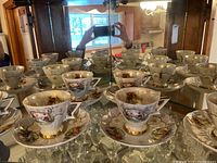 Overall display of six hand painted L’Amour China Japan 110 teacups and saucers inside a glass cabinet, showing the full set.