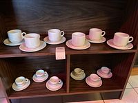 Image showing the full lot with 6 white Steelite coffee cups with saucers on top shelf and 6 smaller Faema espresso cups with saucers on bottom shelf.