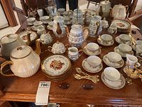Full view of assorted tea service, tableware, and decorative pieces on wooden table.