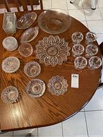 Overall layout of the vintage glass servingware set on a wooden table, showing a variety of bowls, platters, dishes, and sundae glasses.