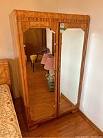 Front view showing two full-length mirrored doors on wood veneer case.