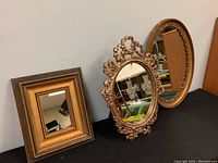 Three vintage framed wall mirrors shown side by side, including an oval SYROCO mirror, an ornate oval mirror, and a rectangular wooden frame mirror.