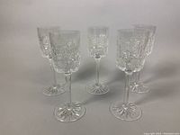 Five vintage crystal goblets arranged in a semicircle showing their pattern and shape