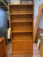 Front view showing full height bookcase with three shelves and bottom cabinet with doors.