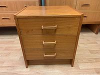 Front view showing three drawers, teak handles, and condition of the tabletop.