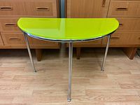 Front view of demi-lune table assembled showing glass top and chrome legs