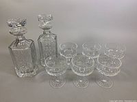 Photo showing the full lot of vintage crystal barware including the pair of decanters and six champagne/sherbet glasses arranged in two rows.