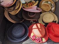 Photo of various vintage hats showing diversity in styles, colors, and floral decorations in the lot