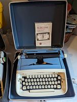 Blue Royal Aristocrat no. 5 manual typewriter inside an open carrying case with paperwork included.