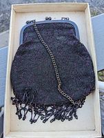 Full view of the antique beaded evening purse in its box. Shows overall shape, beaded fabric, metal frame, chain strap and fringe tassels.