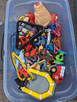 Top view of bin containing assorted toys including action figures, toy vehicles, and accessories.