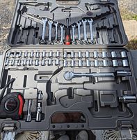 Open case shows assortment of chrome combination wrenches, sockets, ratchet, screwdriver handle, and tape measure.