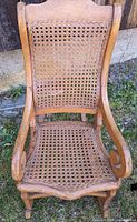 Full front view of the child's rocking chair showing wooden frame and caned backrest.