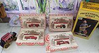 Four original boxed fire truck models arranged on table with Wells Fargo wagon model and Emmet Kelly professional series box visible.