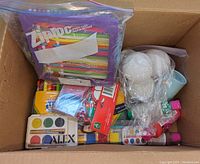 Box of assorted markers, liquid paint tubes, watercolors, and craft supplies in plastic bags