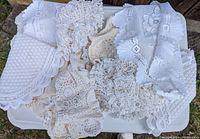 Top view of assorted crochet and lace doilies in white and cream colors laid out on a tray.