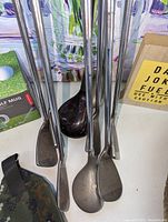 Close-up view of golf club heads including wood and irons, metal shafts visible, Spalding branding on one club.