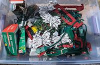 Bin containing multiple bundled Christmas light strands both green and white wired, two green boxes labeled '100 Icicle Lights', and multiple red plastic light stakes.