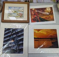 Four prints laid out on surface, one framed print in wooden frame, three prints loose with one wrapped in plastic