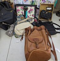 Multiple purses of various materials including leather, canvas, and fabric seen on a flat surface. Photos show a variety of styles and colors including floral and solid.