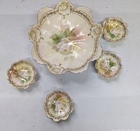 Top view of the large nut bowl and four smaller matching bowls, showing floral painted design with gold-trimmed scalloped edges.