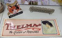 Overview photo of three miscellaneous decorative signs including vintage perfume advertisement, cat illustration, and stone plaque with inspirational quote