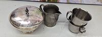 Sterling silver covered dish, pewter pitcher, two stainless steel cups on table