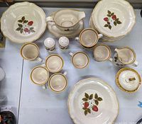 Top view of plates, bowls, cups, creamer, sugar bowl, gravy boat, and salt and pepper shakers with vintage Mikasa Strawberry Festival pattern