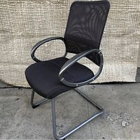 Front and side view of black mesh back office chair with fabric cushioned seat and silver metal armrests and cantilever base.