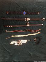 Top view of 7 different fashion choker necklaces on a dark fabric background showing variety of styles and materials
