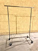 Full view of metal clothing rack showing structure and wheels.