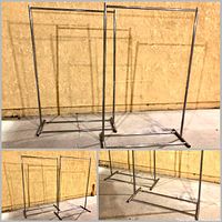 Two silver metal folding clothing racks standing against a wall, showing full height and structure.