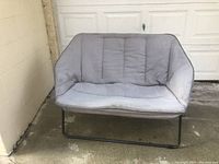 Front view of the folding Papasan loveseat chair with light gray tufted cushion and black metal frame.