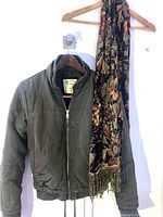 Jacket and scarf hanging on hangers against a white background
