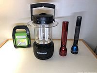 Wide view of Rayovac lantern, green LED light, and two MagLite flashlights on surface.